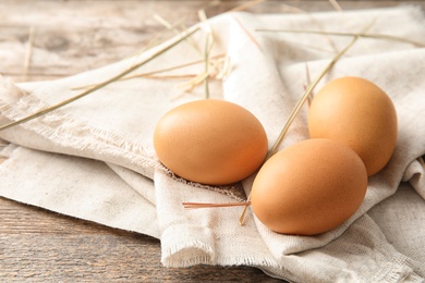 Photo of Raw chicken eggs with sackcloth on wooden table