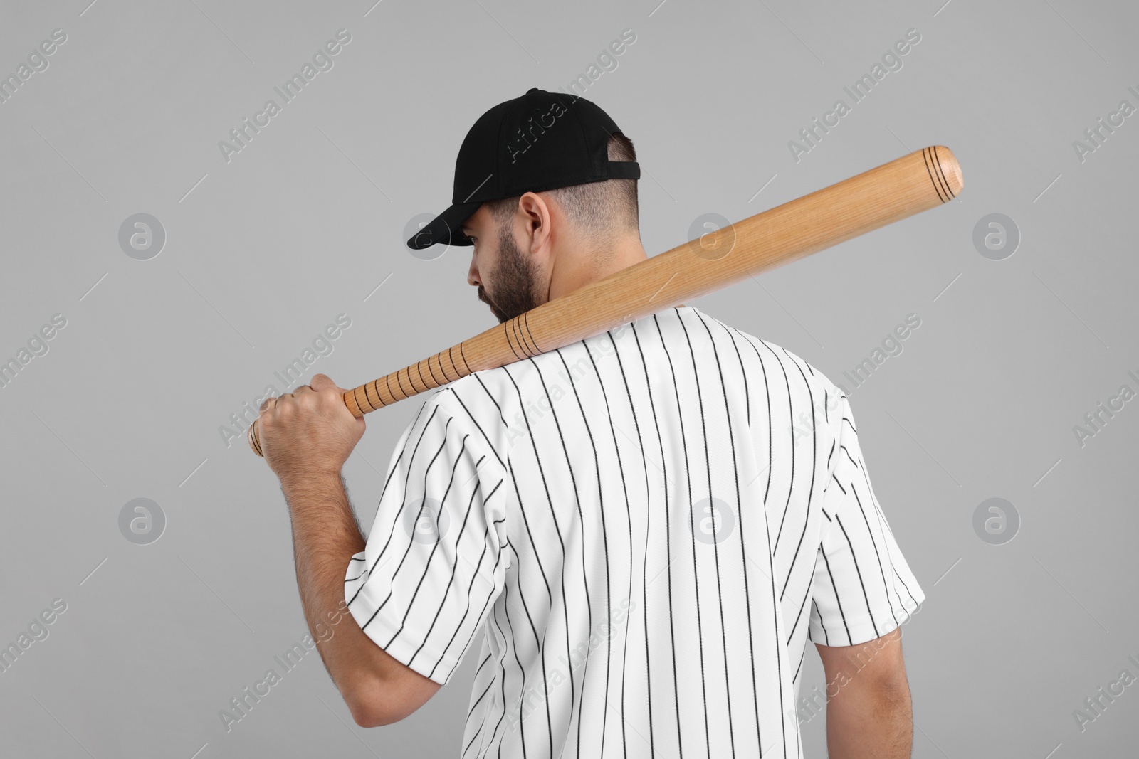 Photo of Man in stylish black baseball cap holding bat on light grey background, back view