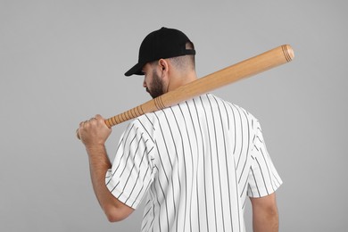 Photo of Man in stylish black baseball cap holding bat on light grey background, back view