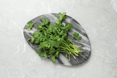 Photo of Bunch of fresh aromatic cilantro on light marble table, top view