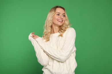 Happy woman in stylish warm sweater on green background