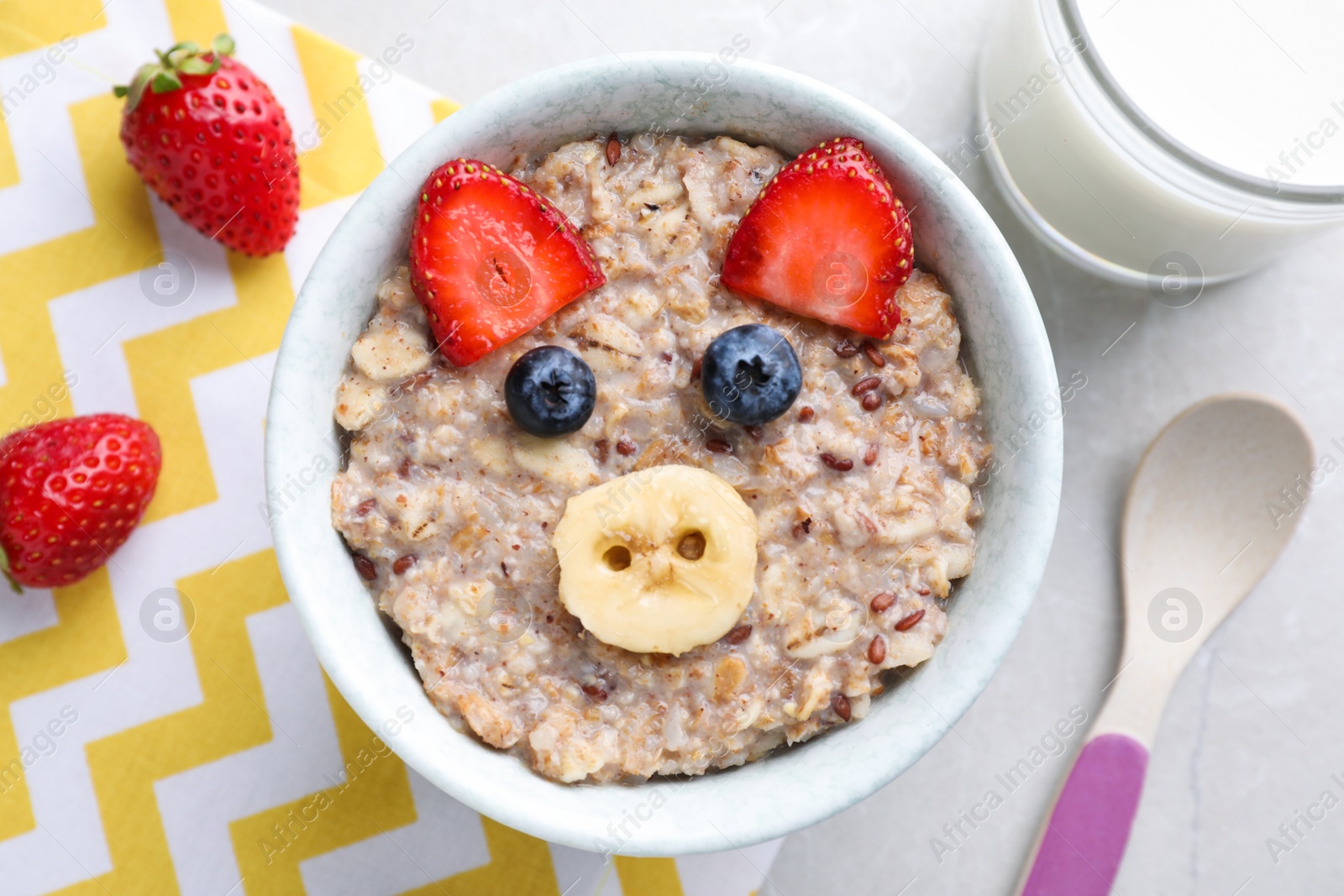 Photo of Tasty porridge served with berries and milk on marble table, flat lay. Creative idea for kids breakfast