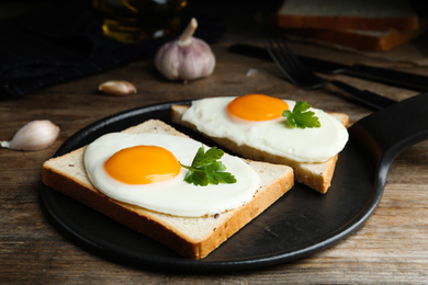 Photo of Tasty fried eggs with bread and parsley on slate board