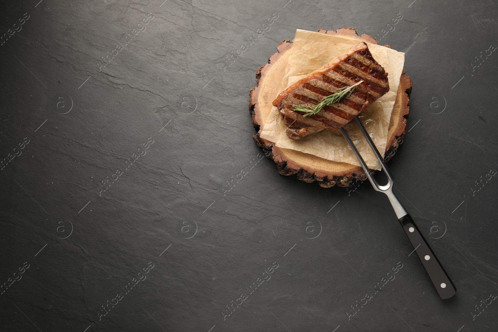 Photo of Delicious grilled beef steak and rosemary on dark gray table, top view. Space for text