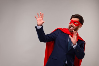 Photo of Businessman wearing red superhero cape and mask on beige background. Space for text