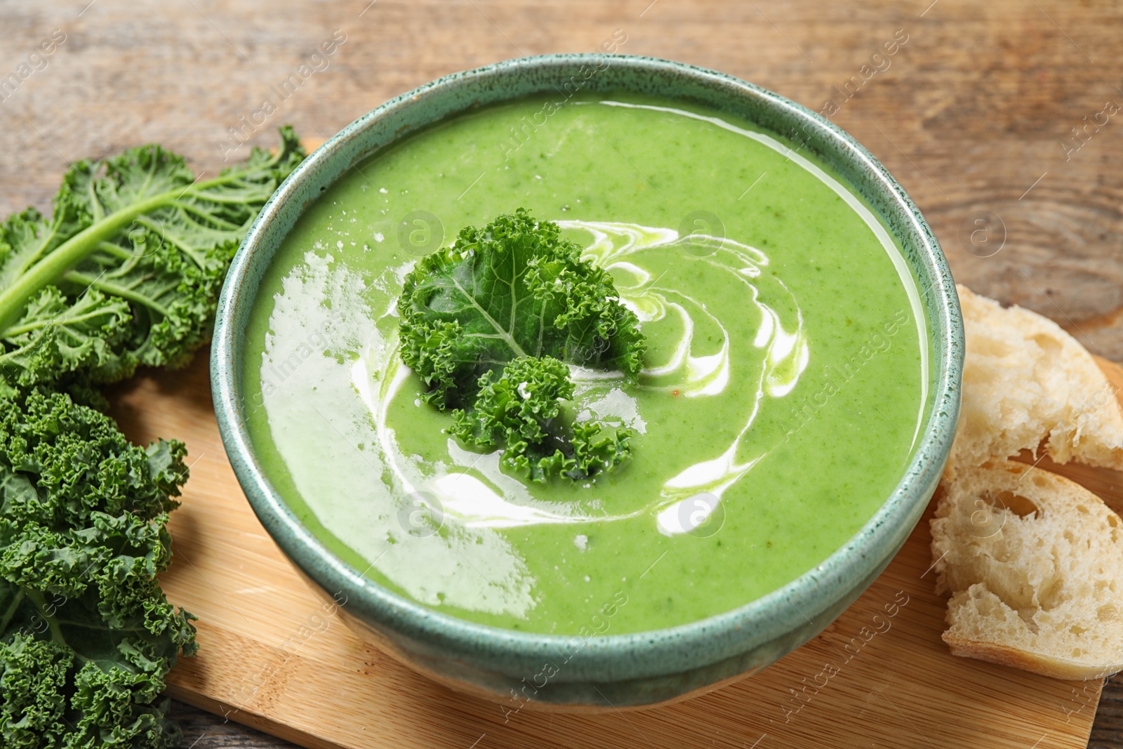 Photo of Tasty kale soup with cream on wooden table