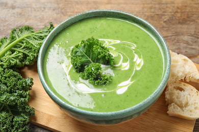 Tasty kale soup with cream on wooden table