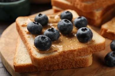 Photo of Delicious toasts with peanut butter and blueberries on table, closeup