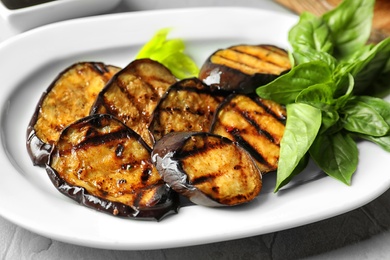 Plate with fried eggplant slices on table, closeup