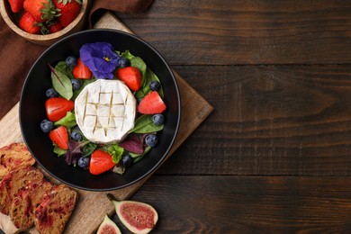 Photo of Delicious salad with brie cheese, blueberries and strawberries served on wooden table, flat lay. Space for text