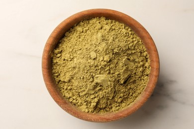 Bowl of henna powder on white marble table, top view