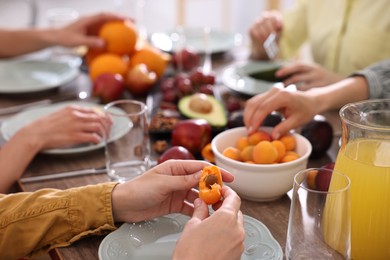 Photo of Vegetarian food. Friends eating fresh fruits at table indoors, closeup