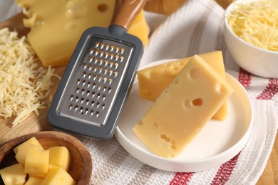 Photo of Grated, cut cheese and grater on table, closeup