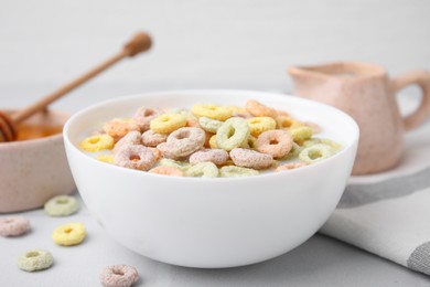 Photo of Cereal rings and milk in bowl on white table, closeup