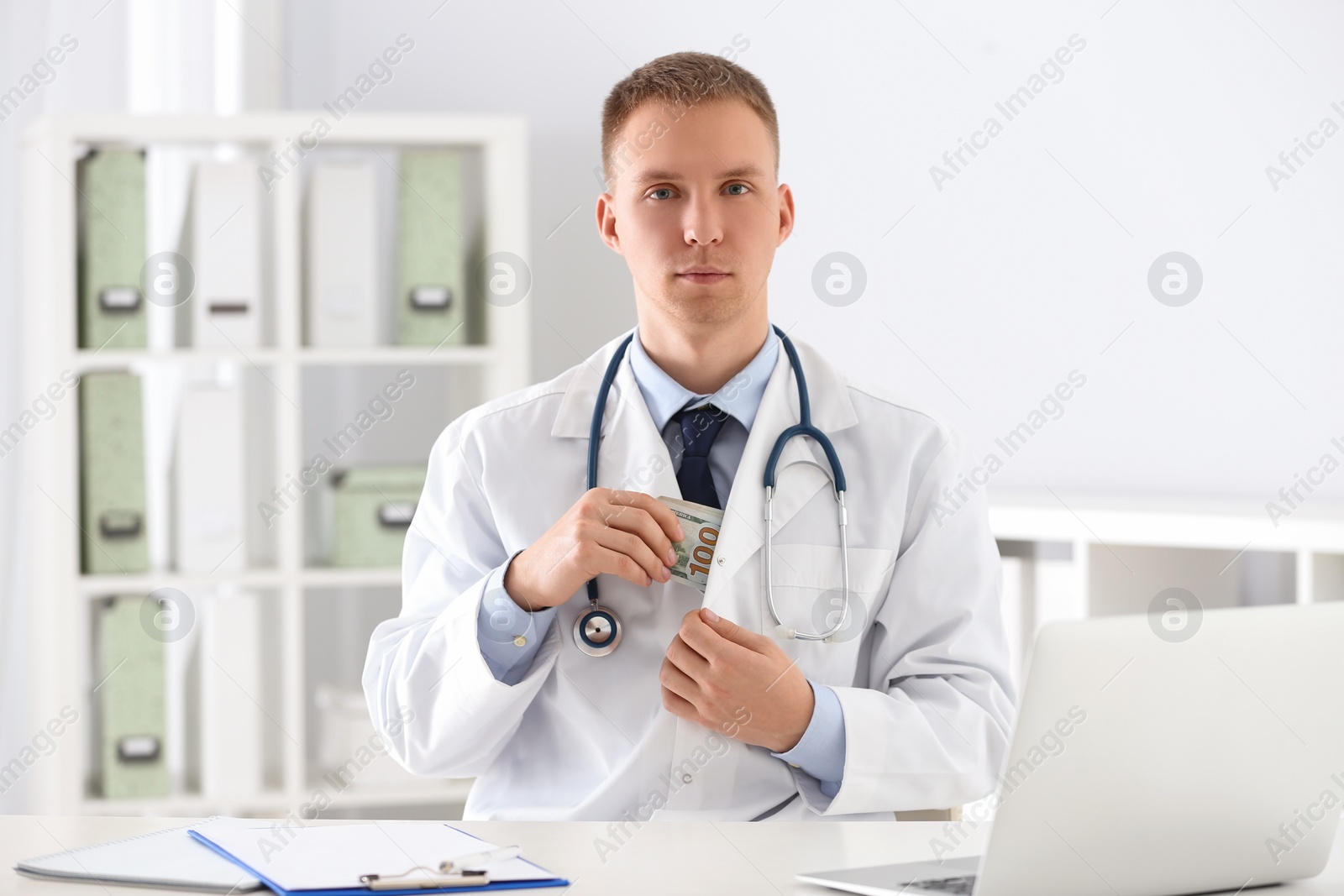 Photo of Doctor putting bribe into pocket in clinic. Corrupted medicine