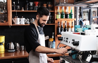 Photo of Barista preparing coffee with modern machine at bar