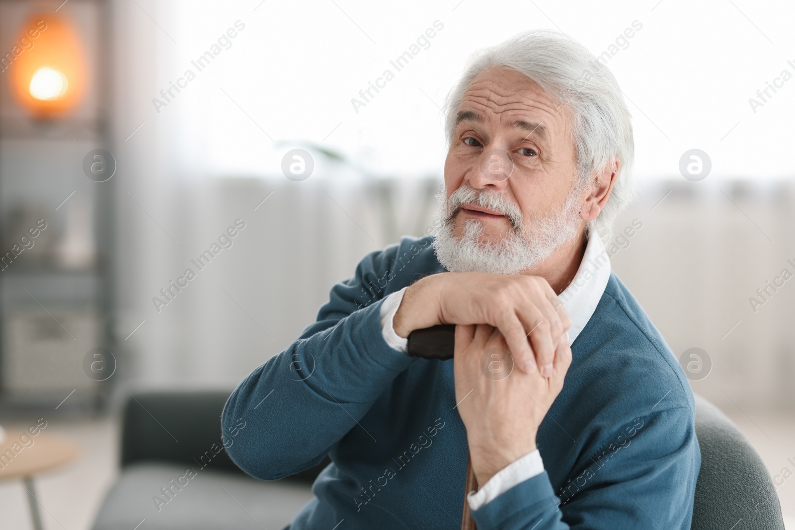 Photo of Portrait of happy grandpa with walking cane sitting on sofa indoors