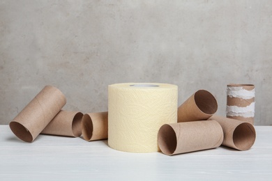 Photo of Full and empty toilet paper rolls on table against grey background. Space for text