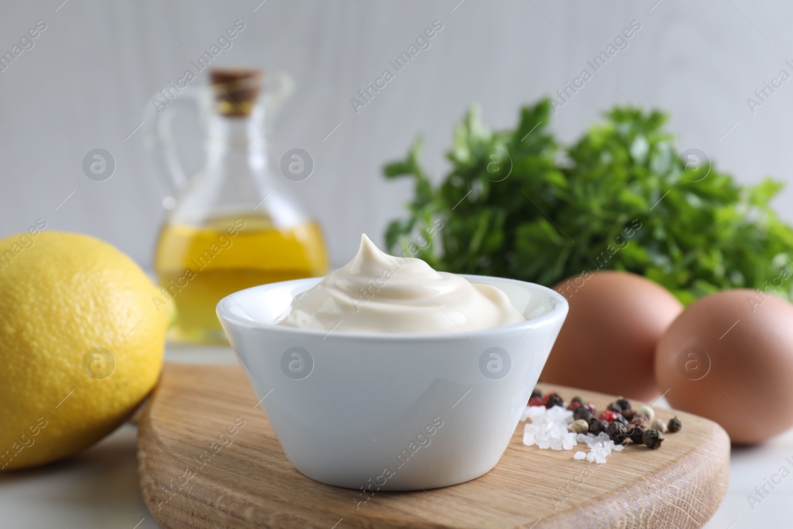 Photo of Tasty mayonnaise sauce in bowl, spices and ingredients on table, closeup