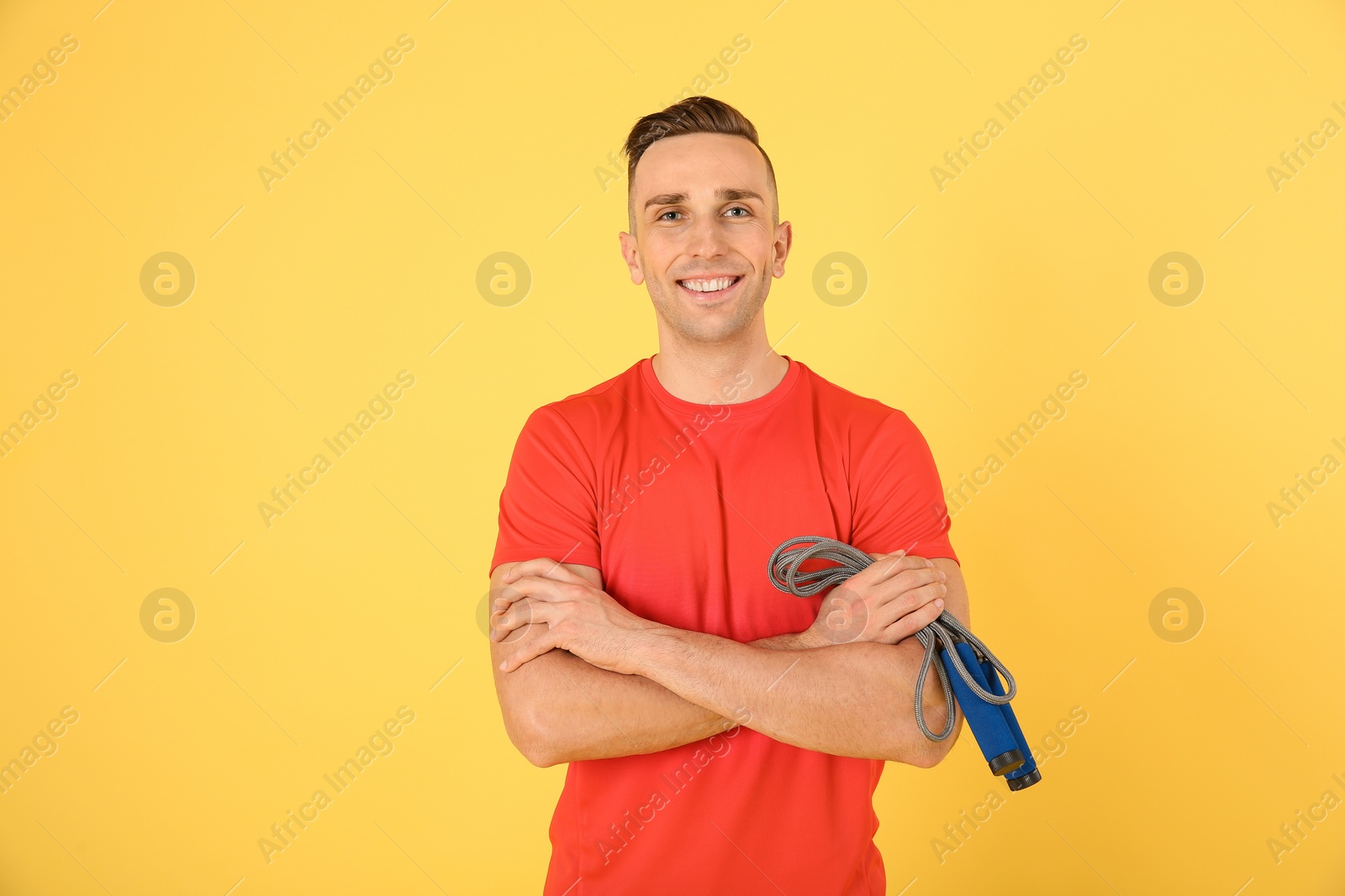 Photo of Portrait of young sportive man with jump rope on color background