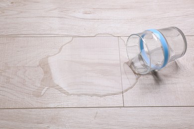 Glass with spilled water on wooden floor