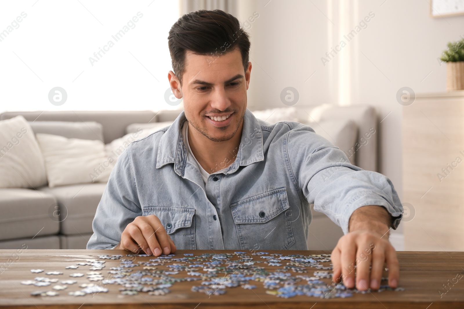 Photo of Man playing with puzzles at wooden table indoors