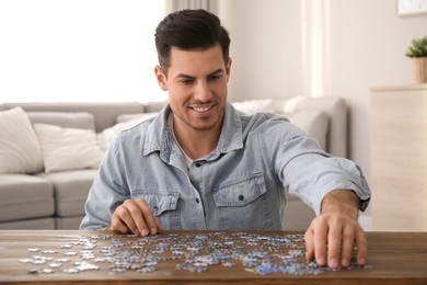 Man playing with puzzles at wooden table indoors