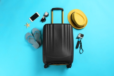 Photo of Flat lay composition with suitcase and traveler's accessories on color background