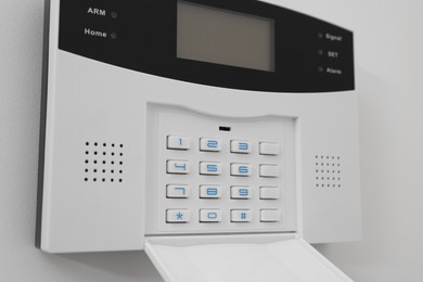 Photo of Home security alarm system on white wall indoors, closeup