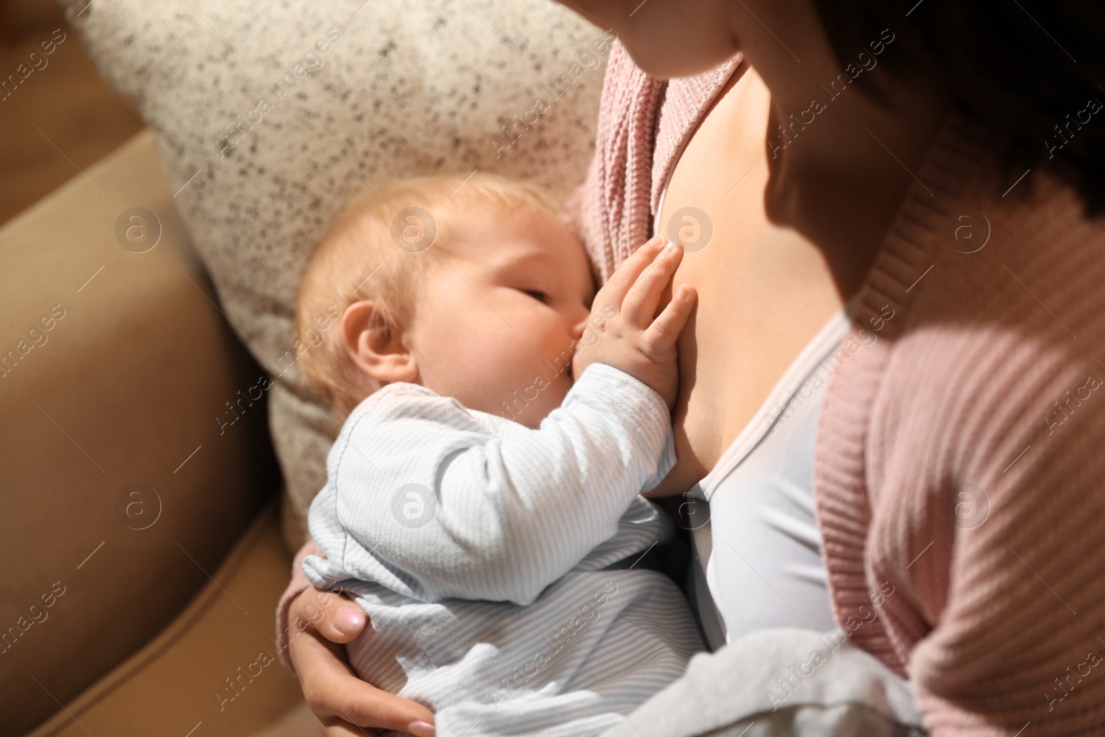 Photo of Woman breastfeeding her little baby at home, closeup