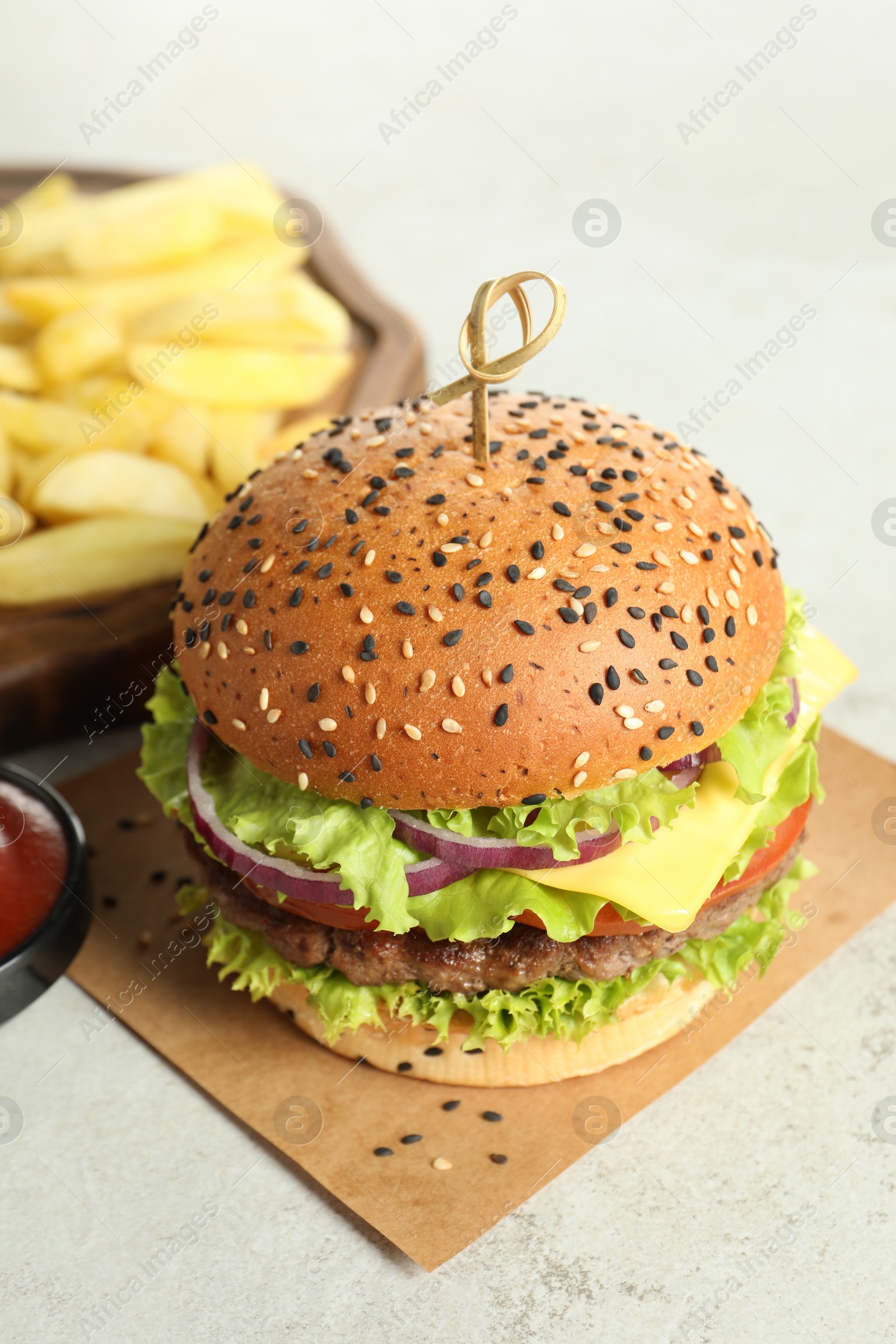 Burger with delicious patty and french fries on light table, closeup Photo of Burger with delicious patty and french fries on light table, closeup