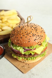 Photo of Burger with delicious patty and french fries on light table, closeup