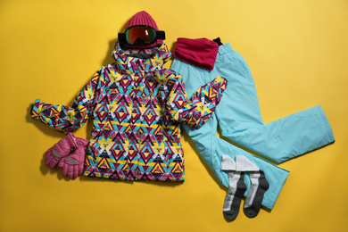 Photo of Stylish winter sport clothes on yellow background, flat lay