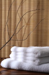 Stacked soft towels on wooden table and tree branches indoors