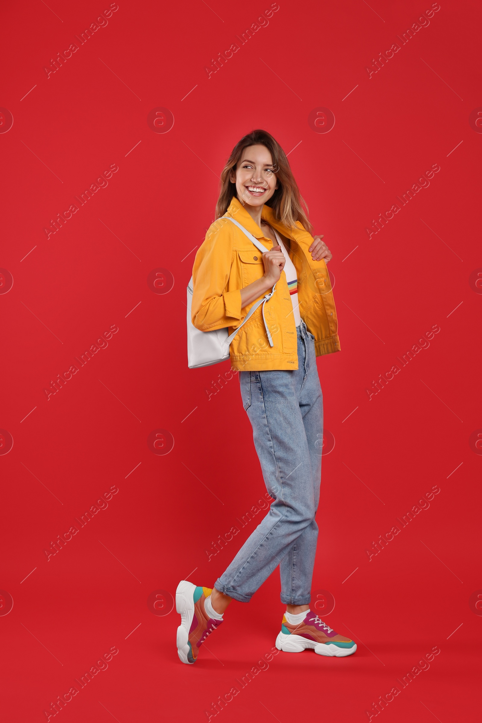 Photo of Happy woman with backpack on red background