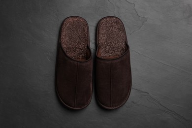 Photo of Pair of brown slippers on dark grey floor, top view