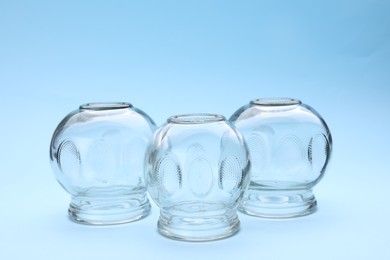 Photo of Glass cups on light blue background. Cupping therapy