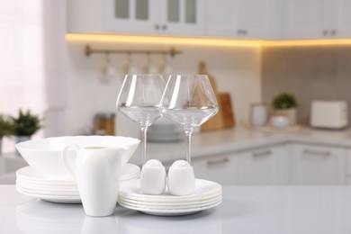 Set of clean dishware and glasses on table in kitchen, space for text