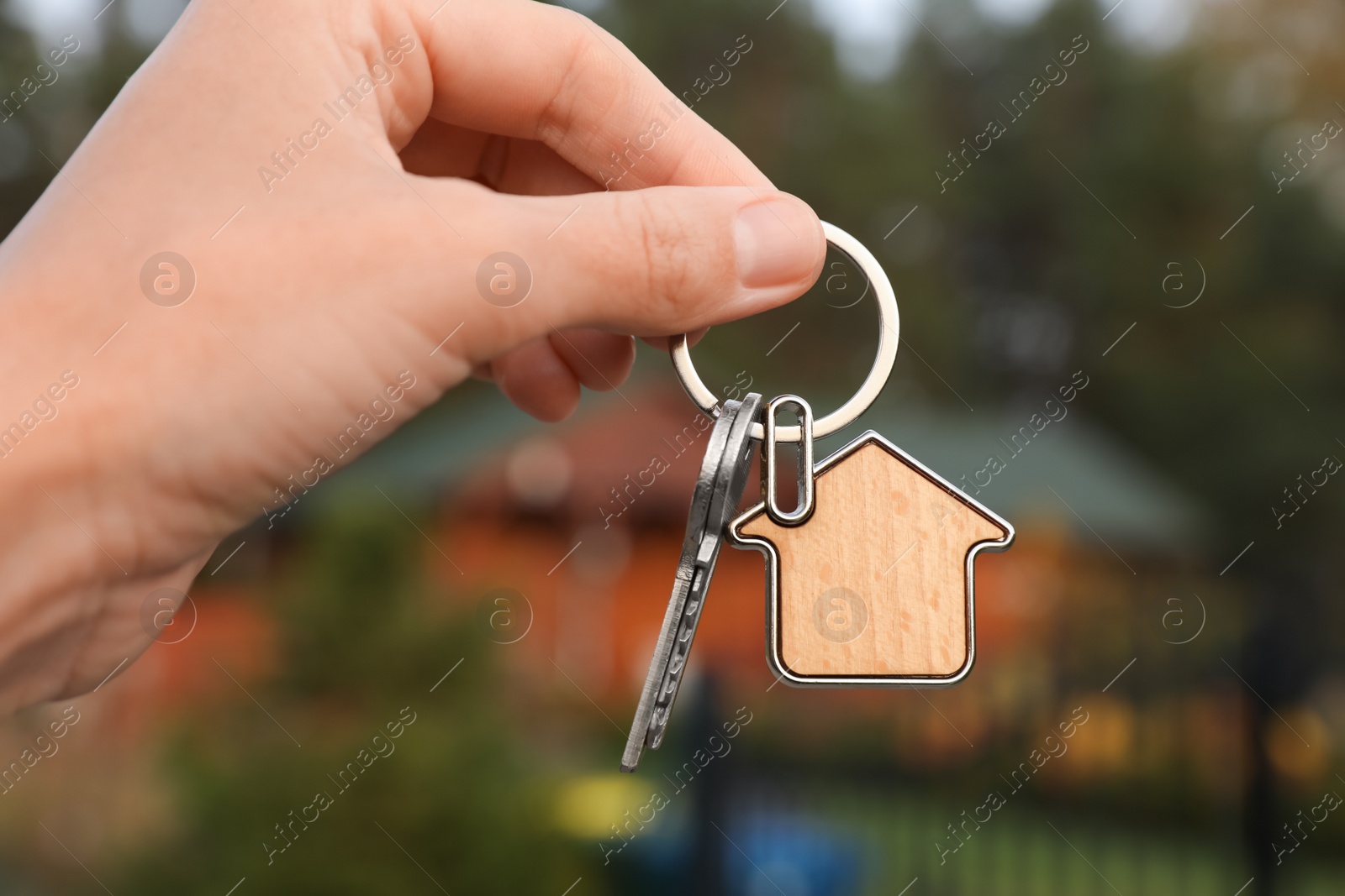 Photo of Woman holding house keys outdoors, closeup. Real estate agent