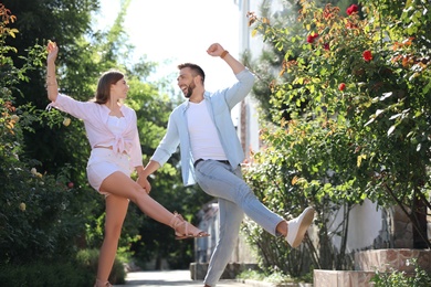 Lovely young couple dancing together in park on sunny day