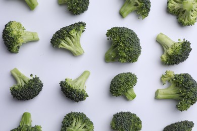 Many fresh green broccoli pieces on white background, flat lay