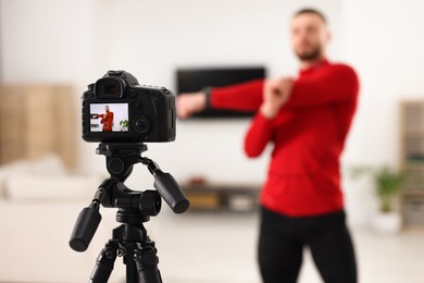 Photo of Trainer recording workout at home, focus on camera. Space for text