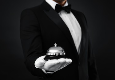 Photo of Butler holding service bell on black background, closeup