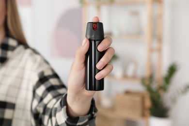 Woman using pepper spray indoors, closeup view