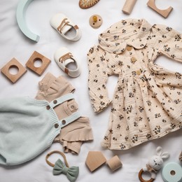 Photo of Layout with baby outfit and cute accessories on white bed, top view