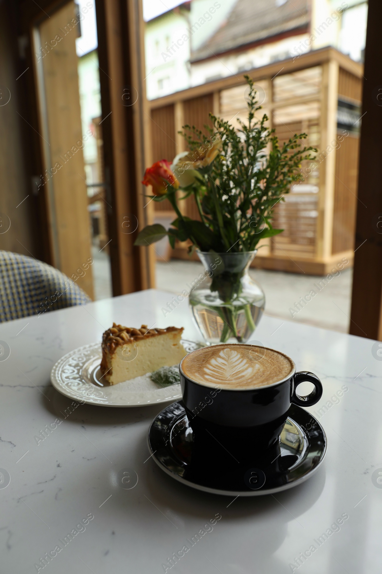 Photo of Cup of fresh coffee and dessert on table in cafeteria