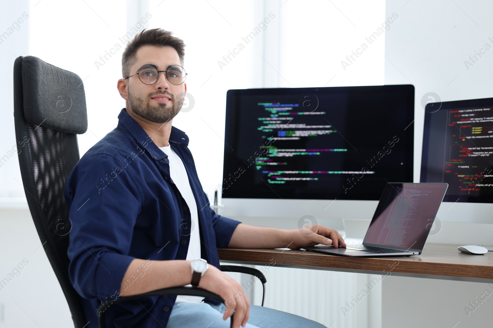 Photo of Young programmer working at desk in office