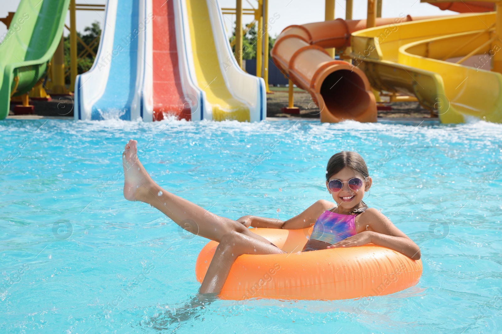 Photo of Cute little girl with inflatable ring in swimming pool at water park