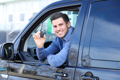 Photo of Man with key sitting in car outdoors. Buying new auto