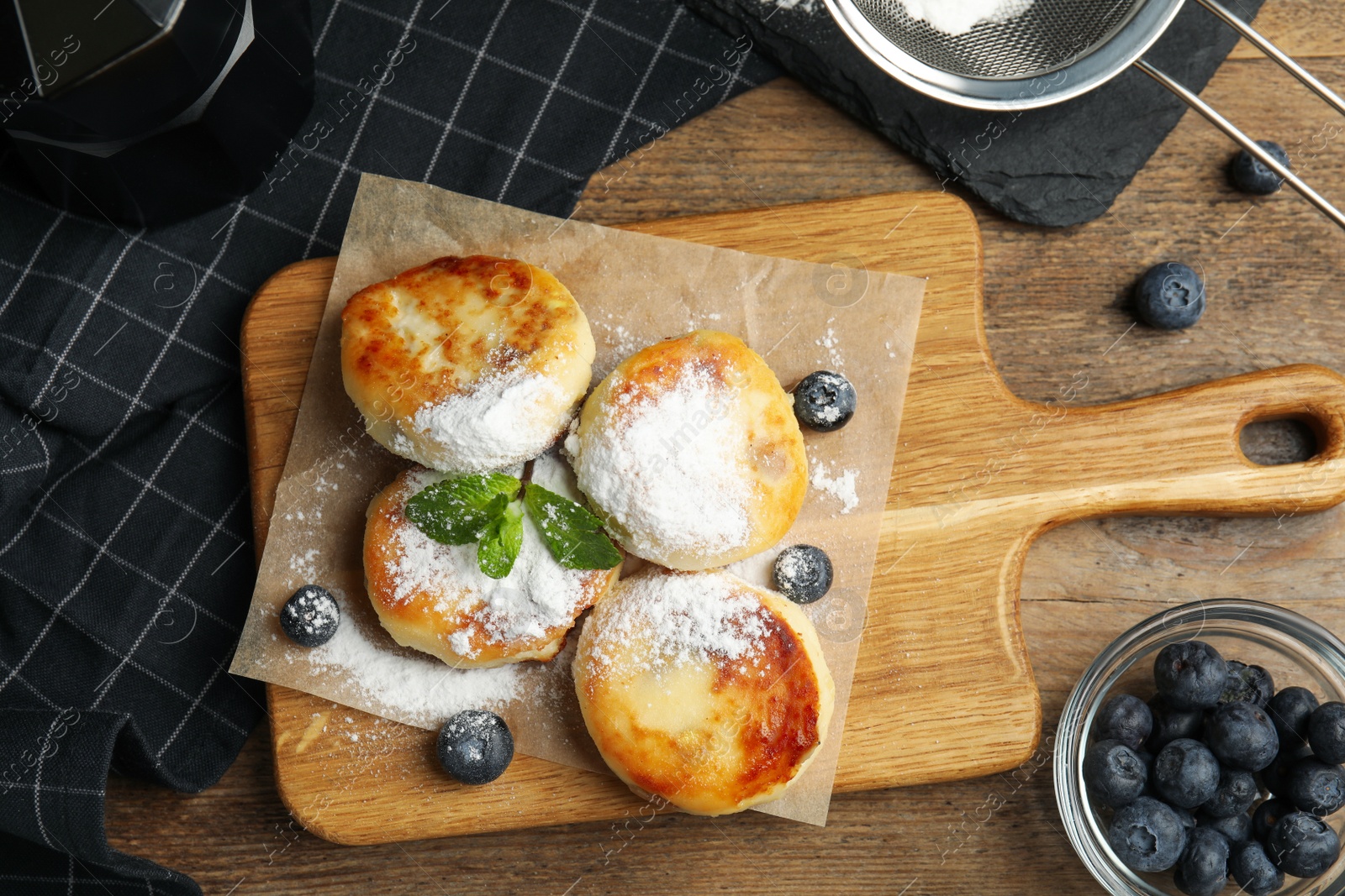 Photo of Delicious cottage cheese pancakes with blueberries and sugar powder on wooden table, flat lay
